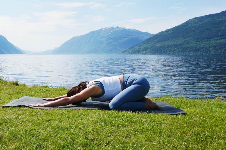 anny johansen viser yogaøvelser foran vakker fjord