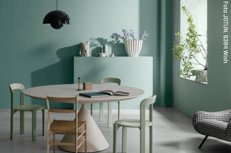 Et rundt grått bord og 4 stoler i et grønt rom