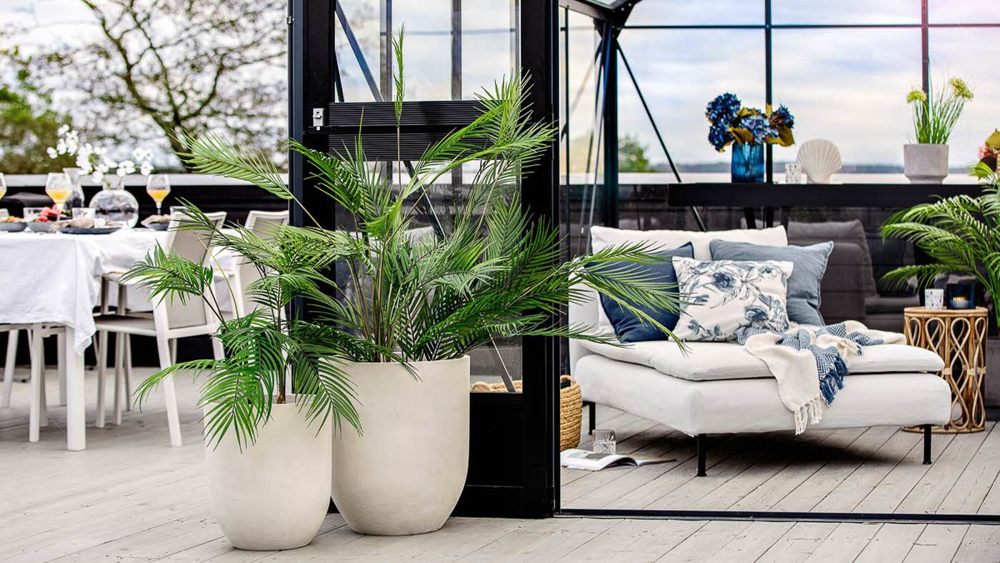 Utemiljø på terrassen med sitteplasser og grønne planter i hvite potter