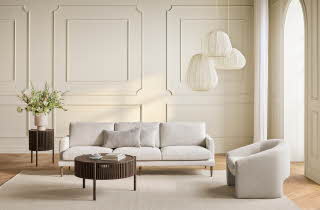 En stue med en hvit sofa, et stuebord, en lenestol og en sidebord med en plante på