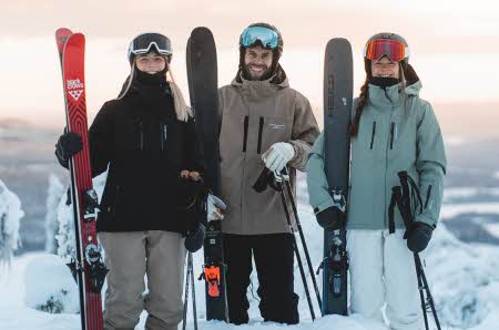 tre personer i vinterklær med ski