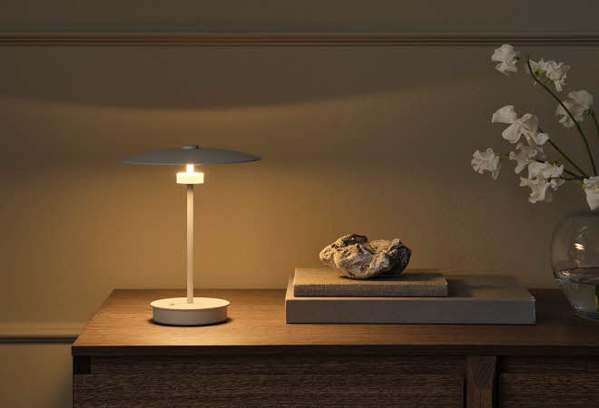 Minimalistisk bordlampe på en trekommode med dekorative detaljer.