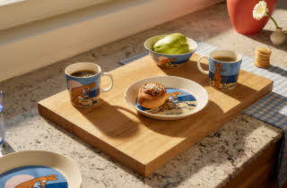 Kjøkkenbenk med to kaffekopper, en bolle med salat og en tallerken med bakverk på et trefat.