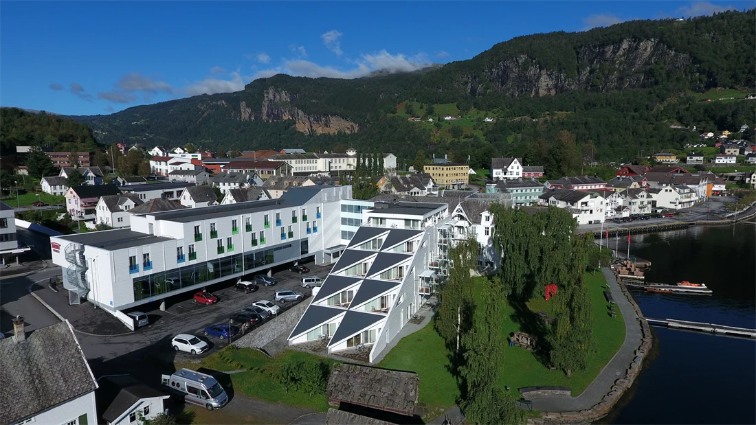 Flyfoto av Thon Hotel Sandven på sommeren med vann i forgrunnen 