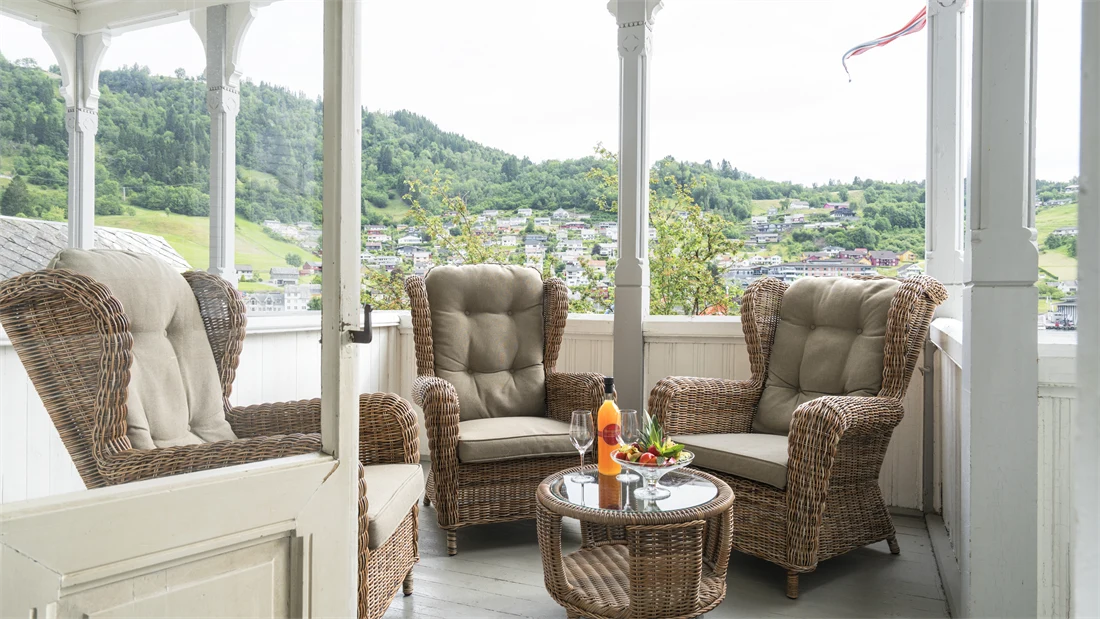 Veranda med peoner på bordet, eplemost i flaske og verandastoler på Thon Hotel Sandven i Norheimsund