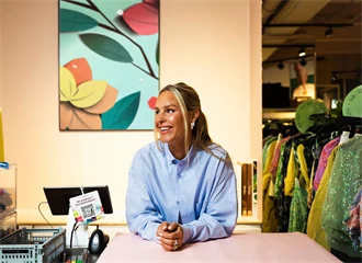 Kaja Sæther, eier av Qomo, står og lener seg på disken til en av butikkene hennes.